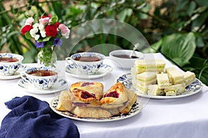 Afternoon tea in the garden with scones, strawberry jam, finger sandwiches with cucumber and egg salad.