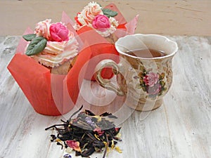 Afternoon tea with roses cupcakes in vintage teacup ans brew on shabby table