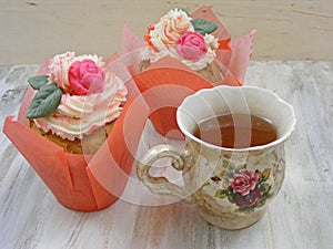 Afternoon tea with roses cupcakes in vintage teacup on shabby table colors of spring