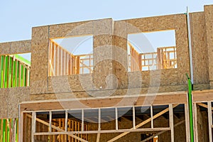 Against the backdrop of a vivid blue sky, the lumber plank accents the house framing in the new residential construction