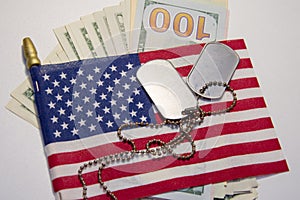 Against the background of the American flag and dollar bills lie army identification medallions. Concept: military pension, salary