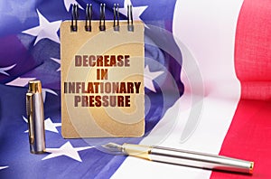 Against the background of the American flag is a notepad with the inscription - decrease in inflationary pressure