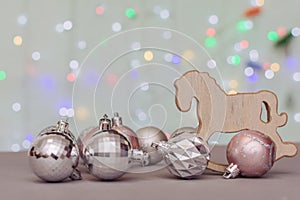 Against the background of bokeh of Christmas lights, Christmas balls and a Christmas tree toy - a wooden rocking horse. Concept -