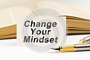 Against the background of the book lies a pen and a business card with the inscription - Change Your Mindset