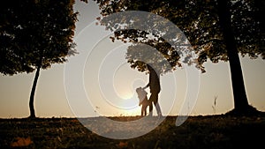 Against the background of the bright orange sunset sky, the silhouette of the father and daughter walking