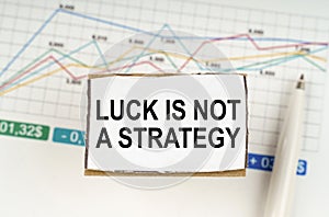 Against the background of business graphics and pens, a sign with the inscription - Luck is Not a Strategy