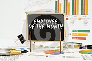 Against the background of business graphs, a board with the inscription - Employee of the Month