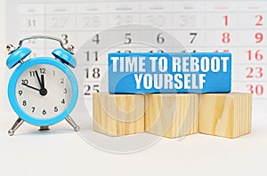 Against the background of the calendar, an alarm clock and a blue block with the inscription -Time To Reboot Yourself