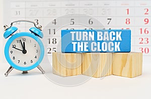 Against the background of the calendar, an alarm clock and a blue block with the inscription - Turn Back the Clock