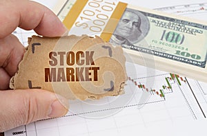 Against the background of dollars and a chart of quotations, a man holds a sign with the inscription - STOCK MARKET