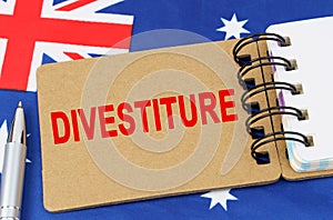 Against the background of the flag of Australia lies a notebook with the inscription - DIVESTITURE