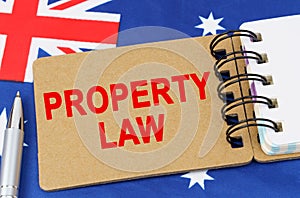 Against the background of the flag of Australia lies a notebook with the inscription - PROPERTY LAW