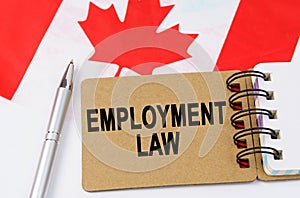 Against the background of the flag of Canada lies a notebook with the inscription - EMPLOYMENT LAW