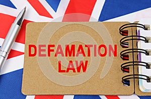 Against the background of the flag of Great Britain lies a notebook with the inscription - DEFAMATION LAW