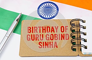 Against the background of the flag of India lies cardboard with the inscription - Birthday of Guru Gobind Sinha