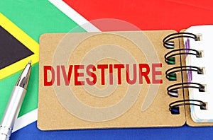 Against the background of the flag of South Africa lies a notebook with the inscription - DIVESTITURE