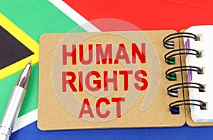 Against the background of the flag of South Africa lies a notebook with the inscription - HUMAN RIGHTS ACT