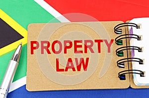 Against the background of the flag of South Africa lies a notebook with the inscription - PROPERTY LAW