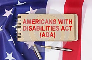 Against the background of the flag of the USA lies a notebook with the inscription - AMERICANS WITH DISABILITIES ACT