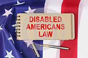 Against the background of the flag of the USA lies a notebook with the inscription - DISABLED AMERICANS LAW