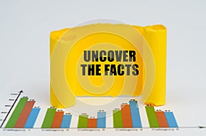 Against the background of the graphs, a yellow paper plate with the inscription - Uncover the Facts