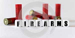 Against the background of rifle cartridges, there are white cubes with text FIREARMS