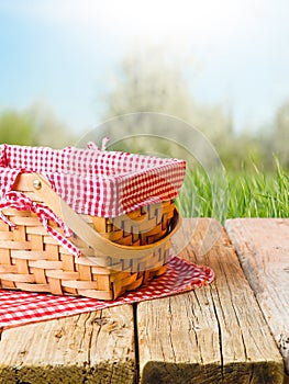 Against the background of summer nature, green grass, a picnic basket on a wooden table. Picnic, rest, relaxation, day off,