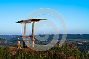 Against the background of the top of the mountain there is a table and benches for travelers tourists lit golden fiery light aroun