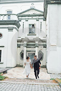 Against big church building. Beautiful bride with his fiance is celebrating wedding outdoors