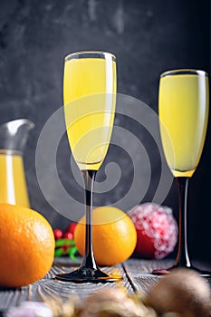 Against a dark background, two glasses with champagne and orange juice. Festive cocktail Mimosa