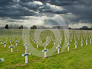 Against dark, threatening skies, rows of graves of WW1 soldiers marked by white crosses in La Targette cemetery near Arras in