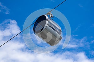 Against the sky on the cable car is moving cabin in the form of a capsule