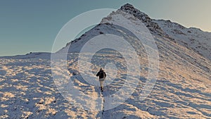 Against a stunning winter backdrop, a hiker bravely treks through the snow, conquering the ascent towards the