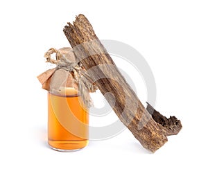 Agarwood, also called aloeswood oudh. With essential oil in pharmaceutical bottle. Isolated on white background photo