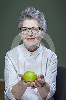 Age, healthy eating, food, diet and people concept - close up of happy smiling senior woman with green apple