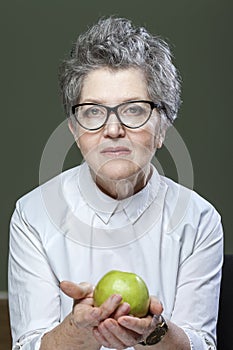 Age, healthy eating, food, diet and people concept - close up of happy smiling senior woman with green apple