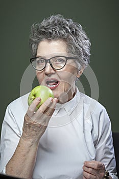 Age, healthy eating, food, diet and people concept - portrait of beautiful old woman biting green apple