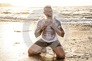 Age is just a number! In healthy body - healthy mind. Handsome fit muscular senior posing in the ocean at sunset time