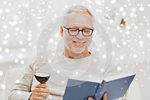 Happy senior man drinking wine and reading book