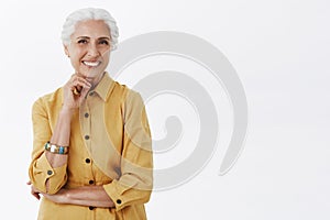 Age is nonsense. Portrait of happy charismatic stylish senior woman with white hair in trendy yellow coat posing with