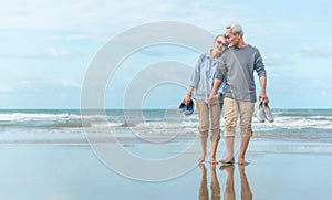 Age, Travel, Tourism and people concept - happy senior couple holding hands and walking on summer beach