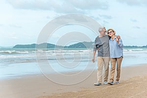 Age, Travel, Tourism and people concept - happy senior couple holding hands and walking on summer beach