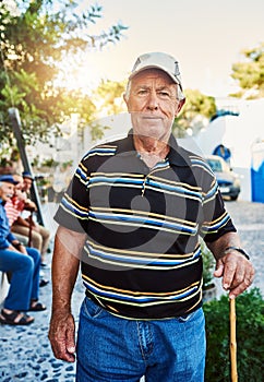 With age you become wiser. Portrait of a cheerful senior man wearing a hat and standing outside while looking at the