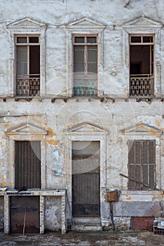 Aged abandoned vintage grunge house facade with broken door and windows and weathered shutters