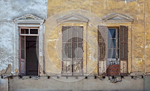 Aged abandoned vintage grunge house facade with broken windows and weathered shutters