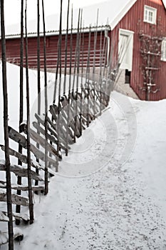 Aged agricultural red traditional barn on idyllic rural farmland, ranch road with snow and rustic old wooden fence photo