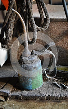 Aged antique dirty oil can centered sitting on an old wooden shelf.