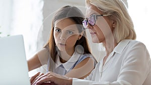 Aged apprentice young mentor working together seated at workplace desk