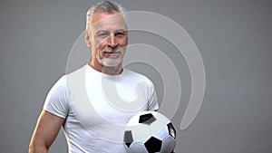 Aged athletic male holding soccer ball, football coach, active lifestyle