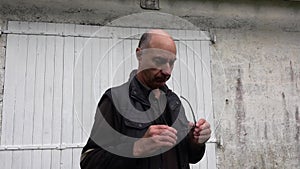 An aged bald man holds glasses in his hands